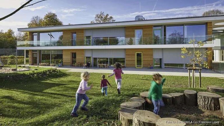 Kita Musikschule lauf, Hintergrund Hausvon außen, Vordergrund vier spielende Kinder im Garten